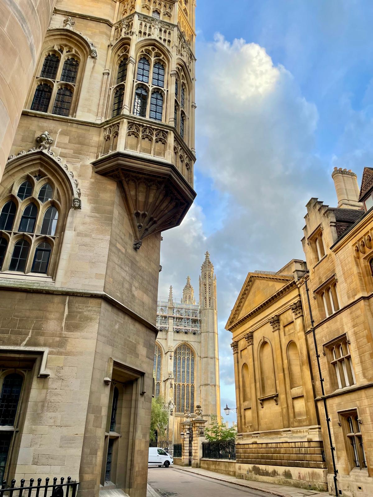 Historic stone buildings and a gothic tower in Cambridge beneath an open sky